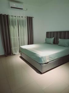 a bed sitting in a room with curtains at Santorini Apartments 1D F5 U8 in Negombo