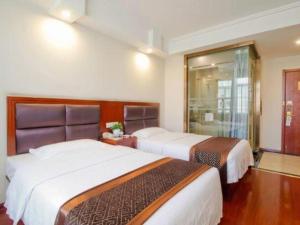 a hotel room with two beds and a window at GreenTree Inn HeFei LongChuan Road South Hefei Railway Station Business Hotel in Hefei