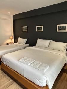 two beds in a bedroom with a black wall at BR Hotel & Residence (Parking is available 250 meters away from the property) in Ban Rong Khoei