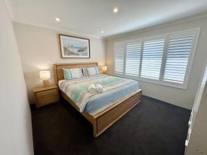 Un dormitorio con una cama y una ventana grande. en Broadwater Beach Cottage, en Broadwater
