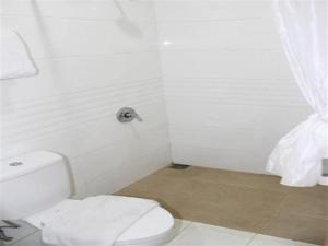 a white bathroom with a toilet and a shower at Kingstone Hotel in Bogor +27 photos