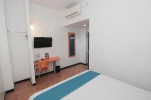 泗水Oriza Hotel Surabaya的一间有床、书桌和电视的房间