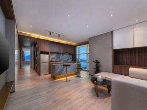 a living room with a couch and a table and a kitchen at Maihao International Hotel in Zhuhai