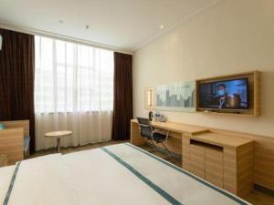 Cette chambre dispose d'un bureau et d'une télévision murale. dans l'établissement City Comfort Inn Ezhou Wenxing Avenue Central Hospital, à Ezhou