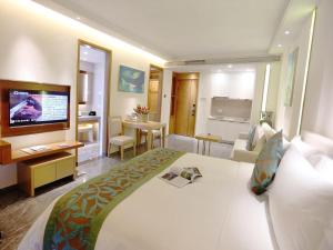 a hotel room with a large bed and a television at Poly Phoenix Hotel in Sanya