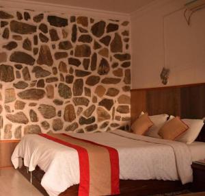 una camera da letto con un muro in pietra con un letto di Stupa Resort a Nagarkot