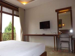 une chambre avec un lit et une télévision au mur dans l'établissement Jimmers Mountain Resort, à Puncak