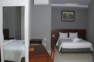 a bedroom with two beds and a table and a mirror at HOTEL GRAND KUTILANG SYARIAH in Bandar Lampung +46 photos