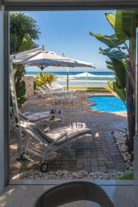 a patio with chairs and an umbrella and a pool at Peacehaven on Sea in Wilderness