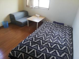 a small bedroom with a bed and a chair at Guesthouse Matsuo B in Fukuoka