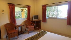 a bedroom with a bed and two chairs and a television at Baan Suan Sook Resort in Chaweng
