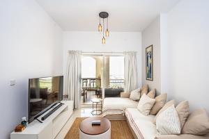 ein Wohnzimmer mit einem weißen Sofa und einem Fernseher in der Unterkunft Serene Lagoon Escape in Ras al Khaimah