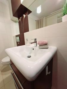 a bathroom with a white sink and a toilet at Apartment SANRiSe in Białystok