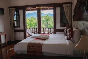 a bedroom with a bed and a large window at The View Pavilion Hotel in Luang Prabang