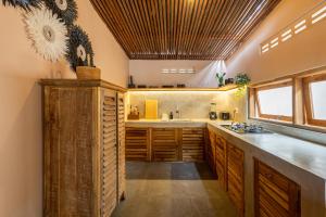 Una cocina con gabinetes de madera y un fregadero. en Villa Yin Uluwatu - Central 1BDR Villa with Pool, en Uluwatu