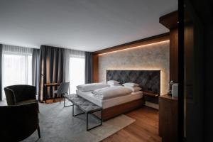 a bedroom with a large bed and a chair at Hotel Alte Post Südsteiermark in Leibnitz