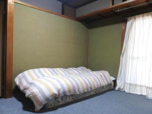 a bed with a striped blanket in a bedroom at Guesthouse Matsuo A in Fukuoka