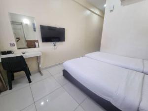 a hotel room with a bed and a desk and a television at Avatel Jelutong in George Town