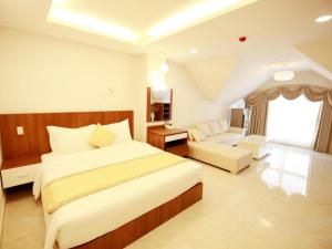 una camera da letto con un letto grande e un soggiorno di Kim Hoa Hotel a Da Lat Altre 38 foto