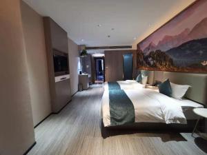 a bedroom with a large bed with a painting on the wall at GreenTree Inn Wuhu Fanchang County Anding Road Hotel in Wuhu