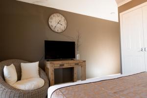 a living room with a television and a clock on the wall at Beach Haven Executive Apartments in Coffs Harbour