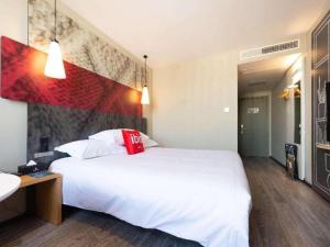 - une chambre avec un grand lit blanc et un oreiller rouge dans l'établissement Ibis Lianyungang Guanyun County Downtown Hotel Hotel, à Guanyun