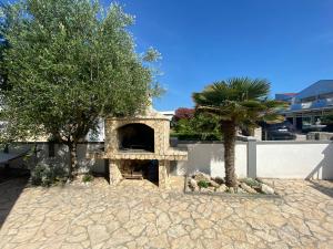 a stone pizza oven sitting next to a palm tree at Apartments Katharina in Batalaži