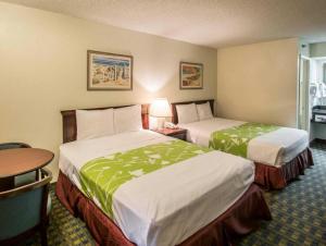 オーランドにあるQuality Inn Kissimmee West - Lake Buena Vista Southのベッド2台とテーブルがあるホテルの部屋