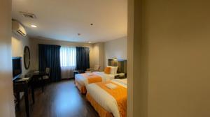 a hotel room with two beds and a desk at Baguio Burnham Suites Hotel in Baguio +156 photos