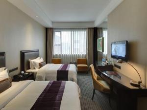 上海市にあるNew Century Manju Hotel Shanghai New International Expo Centerのベッド2台、机、テレビが備わったホテルの部屋