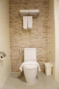 a bathroom with a toilet and towels on a brick wall at The One Residence Hotel in Bangkok