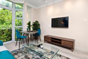 a living room with a table and a tv on a wall at CityPad 1 Bed w Balcony 5 mins to V&A, CTICC in Cape Town