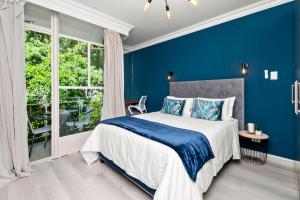 a blue bedroom with a bed and a window at CityPad 1 Bed w Balcony 5 mins to V&A, CTICC in Cape Town