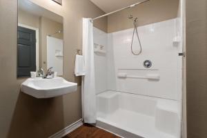a white bathroom with a sink and a shower at Eagle's Den Suites Carrizo Springs a Travelodge by Wyndham in Carrizo Springs +19 photos
