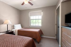 a hotel room with two beds and a window at Eagle's Den Suites Carrizo Springs a Travelodge by Wyndham in Carrizo Springs