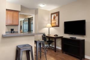 a hotel room with a desk and a tv and a bar at Eagle's Den Suites Carrizo Springs a Travelodge by Wyndham in Carrizo Springs