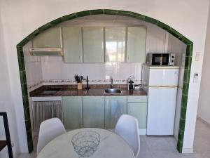 a kitchen with a table and a sink and a refrigerator at Apartamento Calan Forcat in Ciutadella