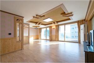 Habitación grande con suelo y techo de madera y ventanas. en Cable Car Pension, en Yeosu