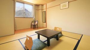a room with a table and chairs in a room at Kamikochi Taishoike Hotel in Matsumoto