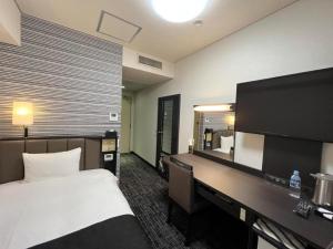 a hotel room with a bed and a desk with a mirror at APA Hotel Owari Ichinomiya Eki-mae in Ichinomiya