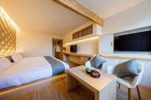 a hotel room with a bed and a tv and a table at RESI STAY Kumico Amaterrace in Kyoto
