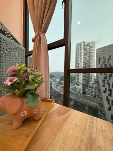 a vase with flowers on a table in front of a window at Casa Boheme Empire Damansara in Petaling Jaya