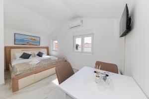 a white bedroom with a bed and a table at Premium Rooms Prince in Zadar
