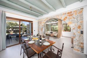 a dining room with a table and chairs and a stone wall at Villa Nineta in Tavronitis