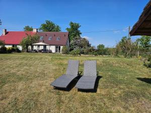 two chairs sitting in a yard in front of a house at Poddasze nad jeziorem Piaski in Wolin