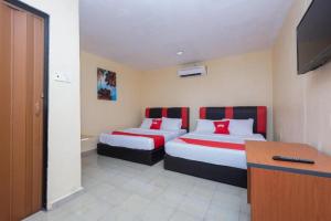a hotel room with two beds and a desk at OYO 89921 Motel New Bay Sg. Lembing in Sungai Lembing
