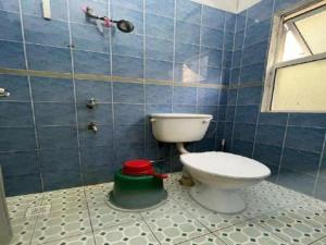 La salle de bains est pourvue de toilettes et d'un mur carrelé bleu. dans l'établissement OYO 90514 Habeeb Lodge Sandakan, à Sandakan