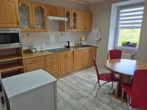 a kitchen with wooden cabinets and a table and a dining room at Apartament nad Włodzicą in Nowa Ruda