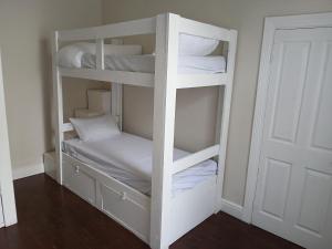 a white bunk bed with white sheets and pillows at Biscuit Mill Woodstock Backpackers in Cape Town +1 photo