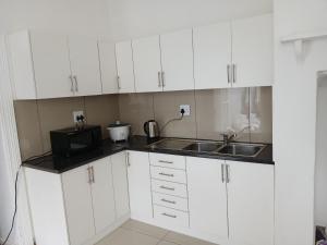 a white kitchen with a microwave and a sink at Biscuit Mill Woodstock Backpackers in Cape Town